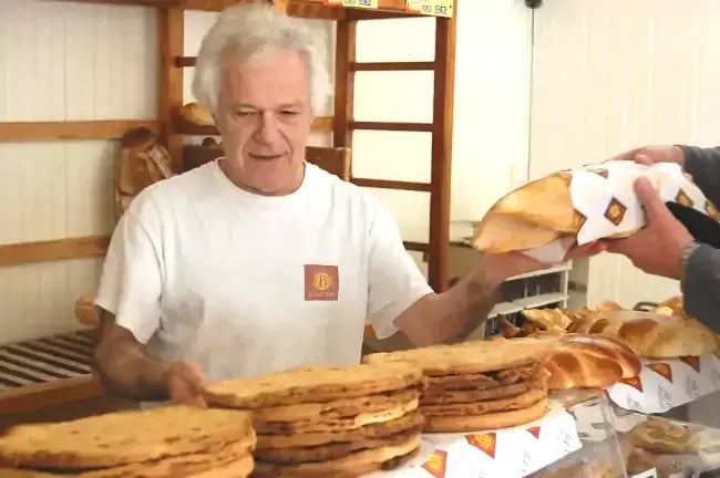 Gérard servant son pain au client de la boulangerie à Fanjeaux